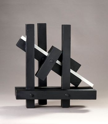 sculpture en noir et blanc composée de blocs posés sur un socle, sur fond gris