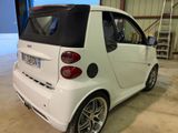 a small white smart car parked in a garage
