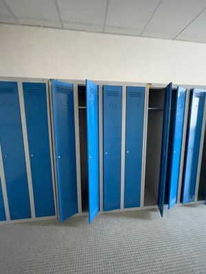 Plusieurs casiers bleus sont alignés les uns à côté des autres dans une pièce vide.