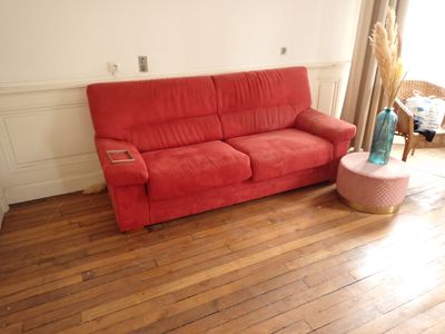 un canapé rouge placé dans un salon près d'une fenêtre
