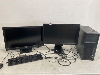 Deux écrans d'ordinateur et un clavier sont posés sur une table