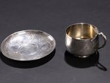 silver cup and saucer on a black surface