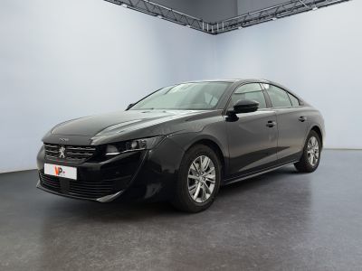 La voiture noire est garée dans une grande pièce aux murs blancs.