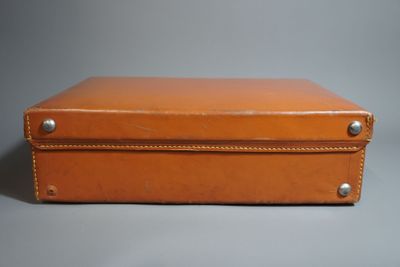 une valise en cuir marron posée sur une surface grise