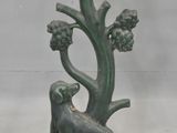 a statue of a dog sitting under a tree with grapes on it