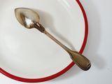 a silver spoon on a white plate with a red rim