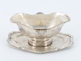 un service ancien en argent composé d'un bol et d'une soucoupe posés sur une soucoupe