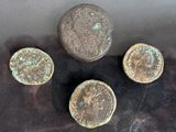 four ancient roman coins sitting on top of a black surface