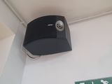 a black paper dispenser on the wall above a sign