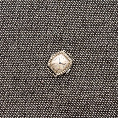 un gros plan d'une bague sertie d'un diamant, posée sur un tissu