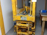a yellow forklift sitting in a room with a table and chairs