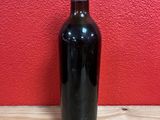 a bottle of wine sitting on a table with a red wall in the background