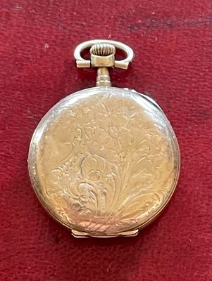 une montre de poche en argent posée sur un tissu rouge