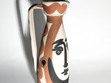 a vase with a face painted on it sitting on a table