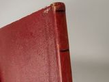 a hand holding a red book on a white surface