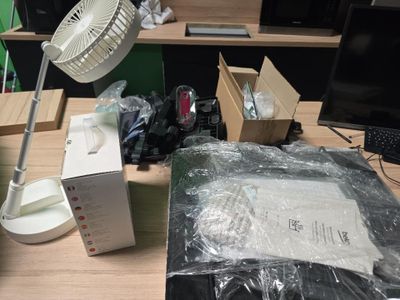 un bureau sur lequel se trouvent un ordinateur, un ventilateur et d'autres objets