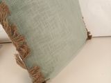 a green pillow with fray edges on a white couch