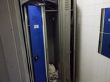 un casier bleu dans un coin d'une salle de bains carrelée de blanc