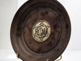 une plaque métallique ornée d'une rose, posée sur un socle