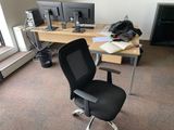 a black office chair sitting in front of a computer desk