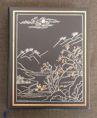 un livre noir et doré avec une illustration représentant des montagnes et des arbres