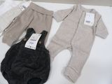 three baby clothes on a table with tags on them