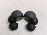 a pair of black ear buds sitting on a tile floor