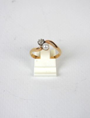 un gros plan d'une bague en or sertie d'un diamant et d'une perle