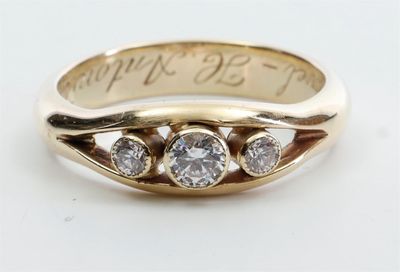 gros plan d'une bague en or ornée de trois diamants