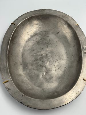 plaque argentée aux bords rivetés sur un fond blanc