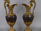 pair of antique bronze and glass vases on pedestals on a gray background