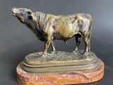 bronze sculpture of a bull on a marble base on a black background