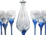 six wine glasses and a decanter set on the table