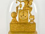 une horloge en or sous un dôme de verre sur une table