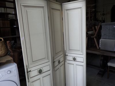 a tall white cabinet with a washer and dryer inside of it