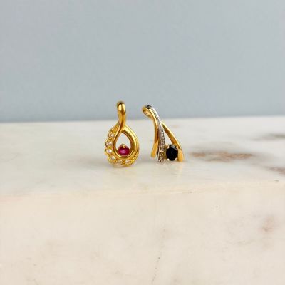 boucles d'oreilles plaquées or ornées de pierres noires et blanches sur un fond marbré