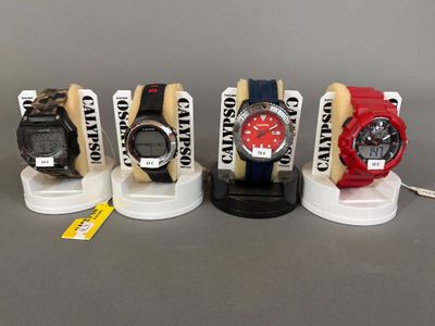 Quatre montres différentes sont exposées sur un présentoir, accompagnées d'étiquettes.
