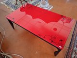 a glass table with a red table top on the floor