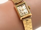an image of a woman ' s wrist with a gold watch on it