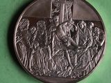 une médaille ancienne en argent représentant un homme sur une croix, entouré de soldats