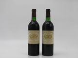 two bottles of wine sitting next to each other on a white surface