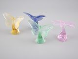 trois figurines en verre de couleurs et de formes différentes posées sur une surface blanche