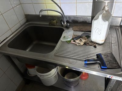 a dirty sink in a dirty kitchen with a bottle of milk