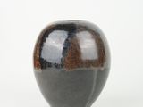 a black and brown vase sitting on a white surface