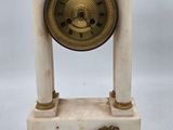 une petite horloge posée sur une table à côté d'une paire de ciseaux