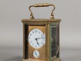 une petite horloge en laiton surmontée d'une vitrine
