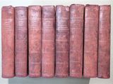 several old books are lined up in a row on a shelf