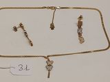 deux colliers en or et une paire de boucles d'oreilles posés sur une surface blanche