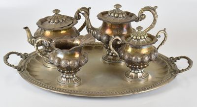 trois théières en argent posées sur un plateau en argent, sur fond blanc