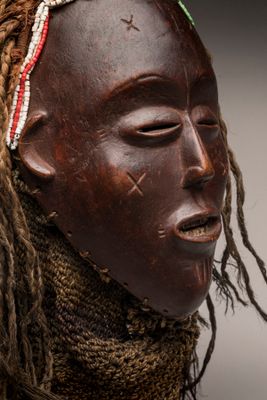 un masque africain orné de dreadlocks et d'un foulard